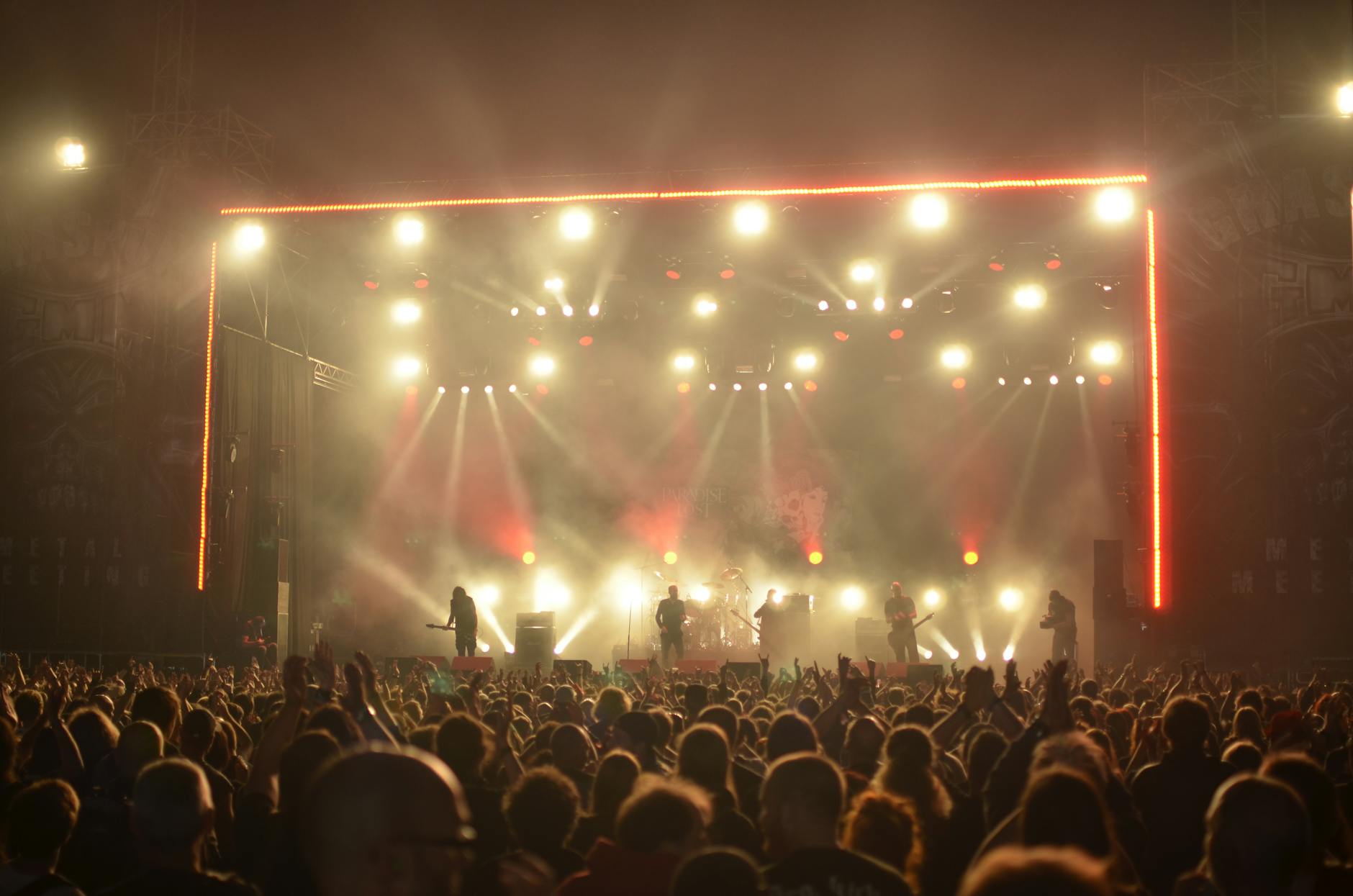 Koncert heavy metalowy nocą, zespół na scenie i szalejąca publiczność