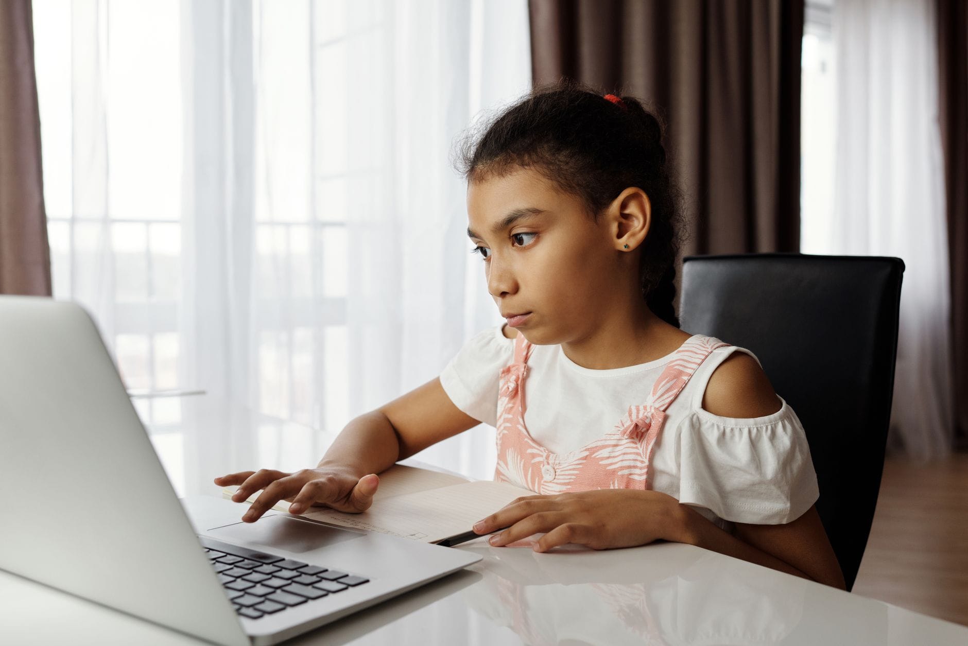 Dziewczynka uczy się samodzielnie przy laptopie w domu