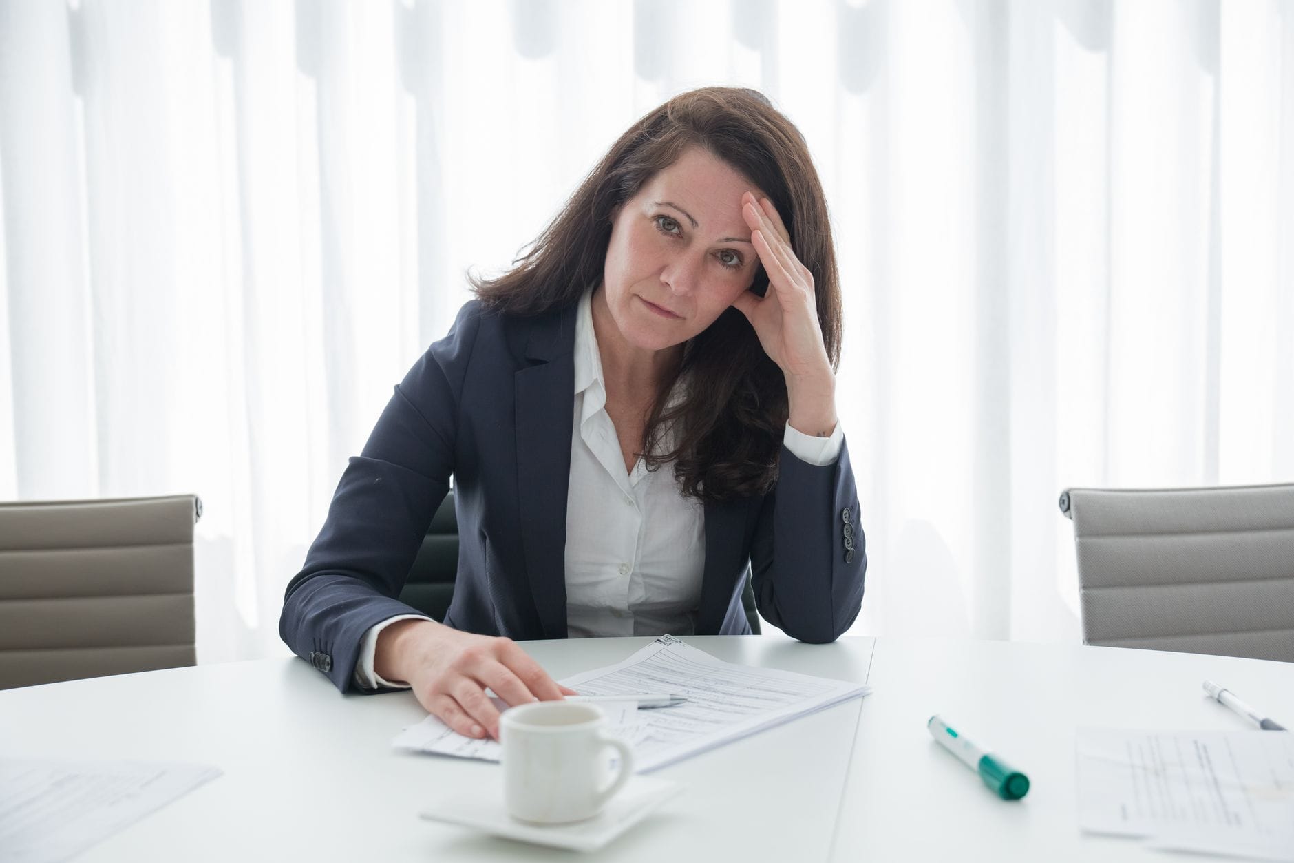 Zestresowana bizneswoman przy biurku z dokumentami, przytłoczona pracą